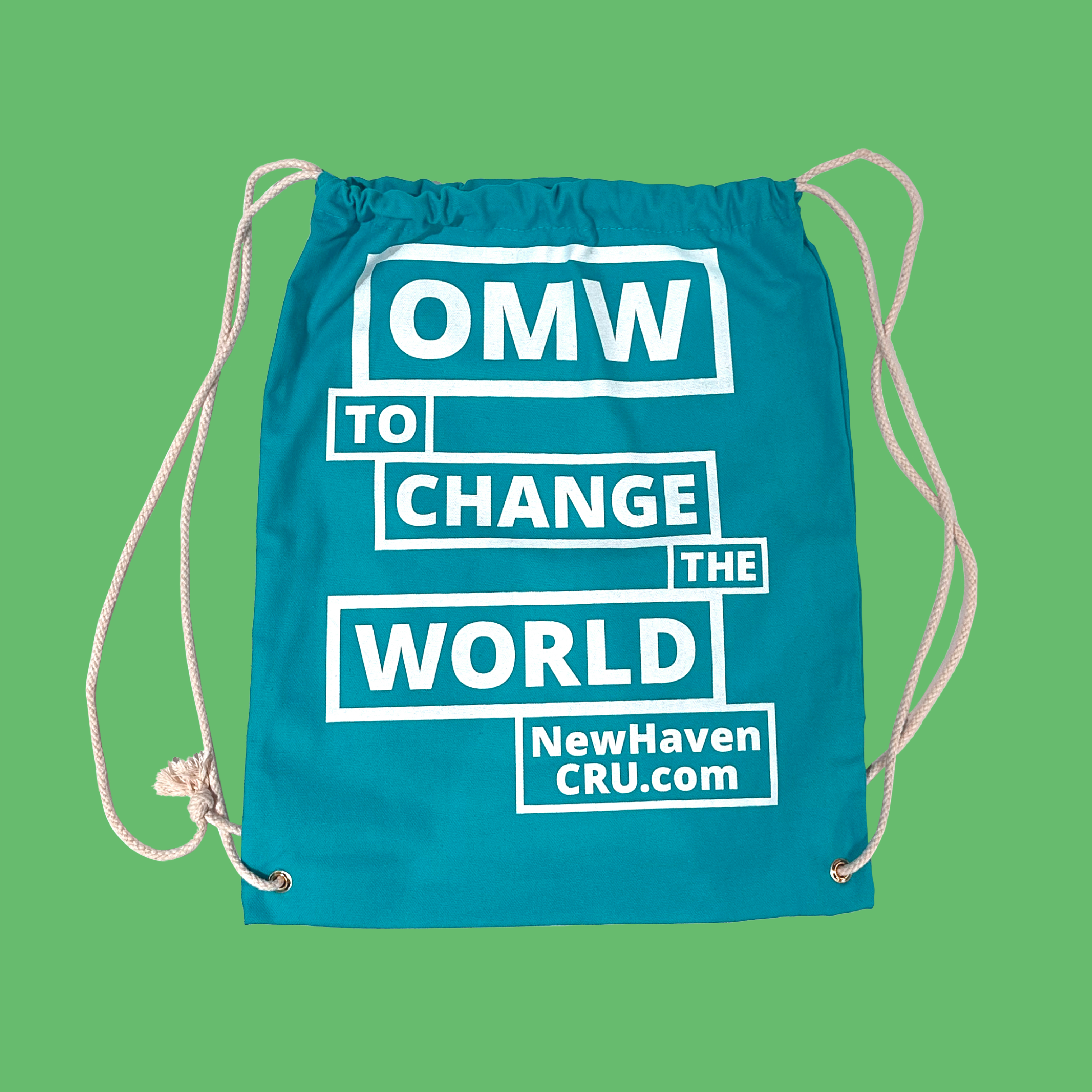 A teal blue canvas drawstring bag on a green background with "OMW to change the world NewHavenCRU.com" imprinted in white lettering.