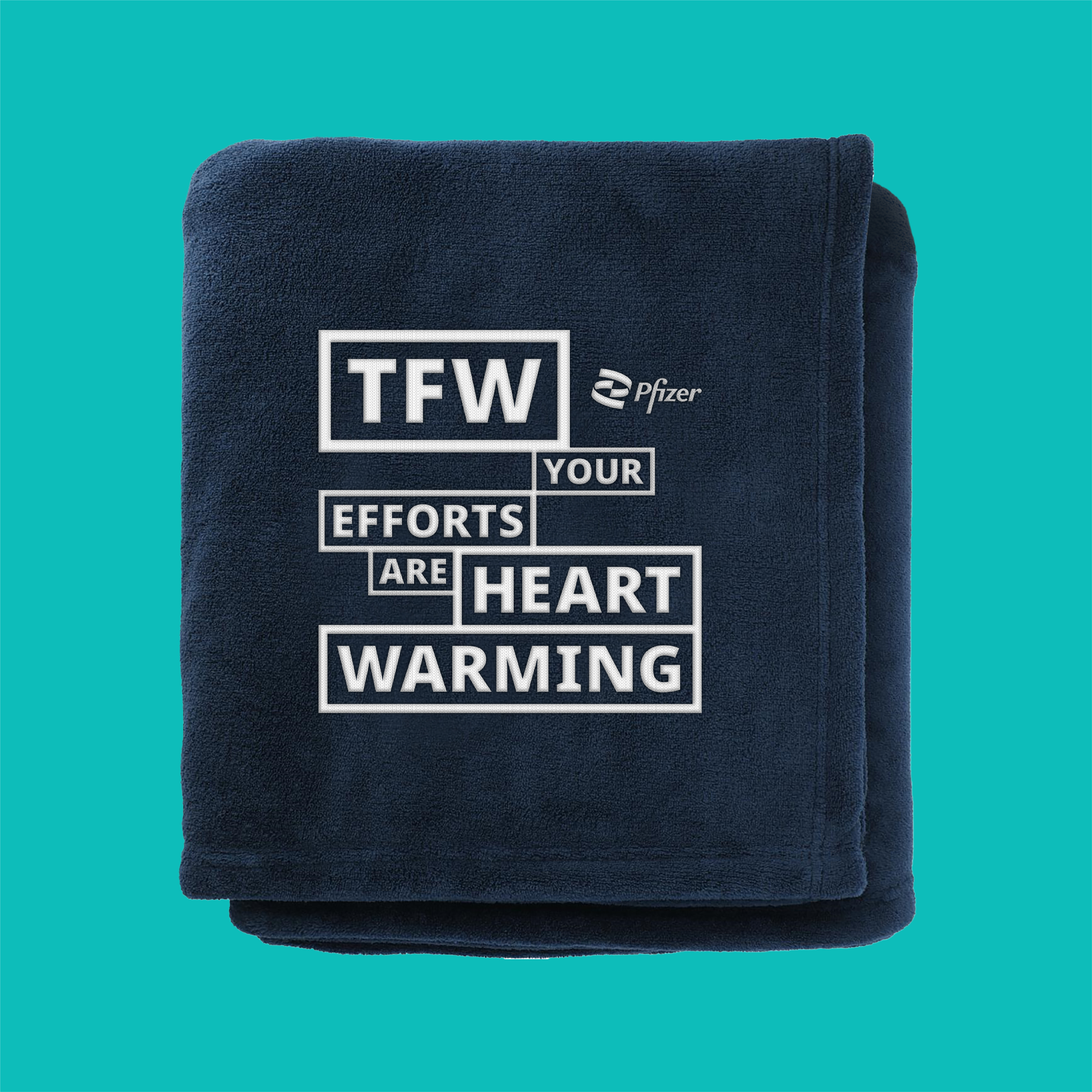 A navy blue fleece blanket folded up on a teal background, with "TFW your efforts are heart warming" embroidered in white lettering.