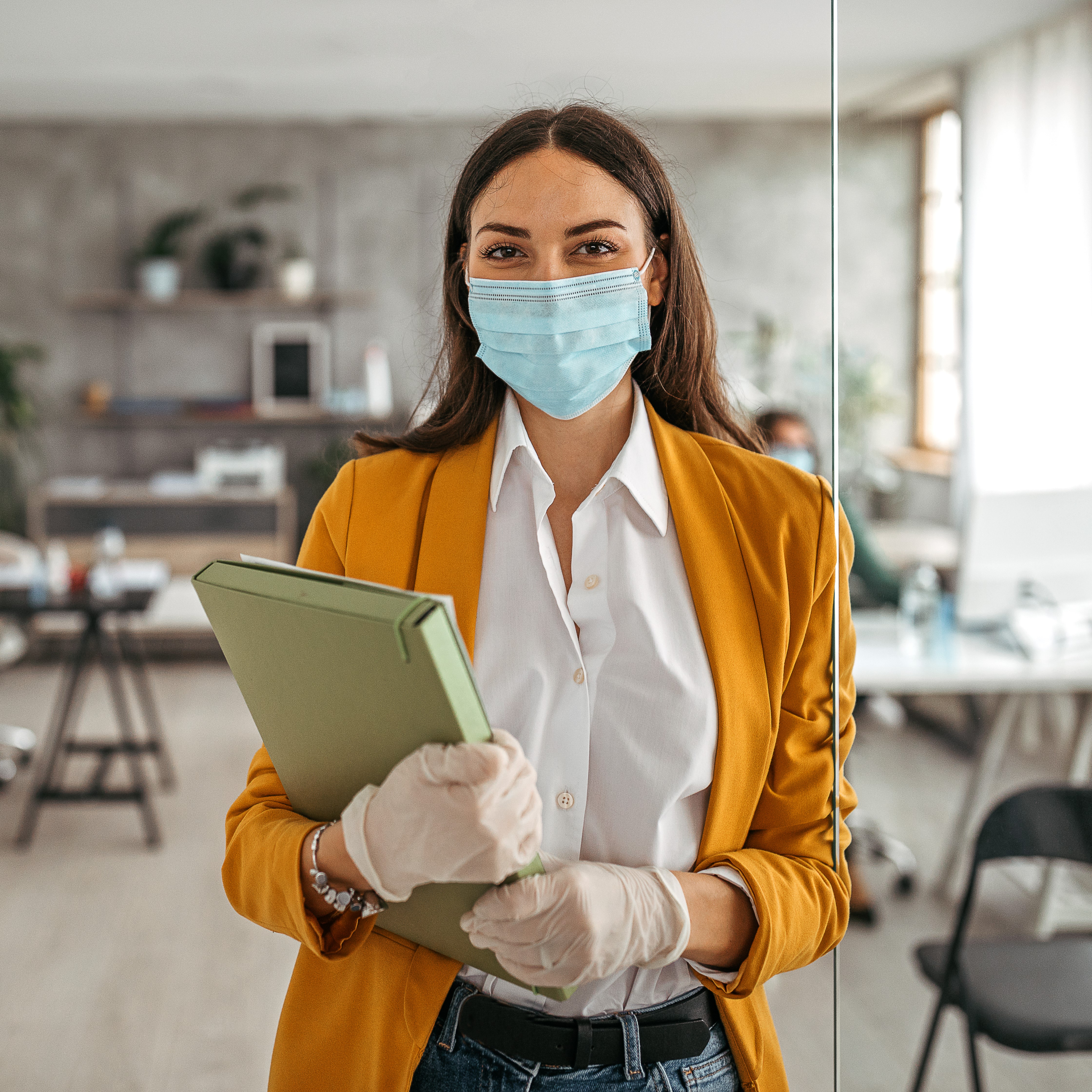 Clinical trial staff holding a clipboard and wearing a surgical facemask and orange blazer
