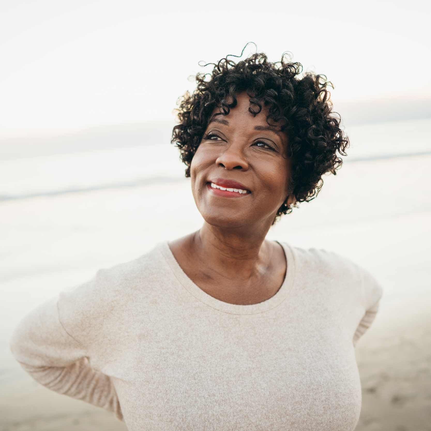 Woman standing on beach looking hopeful | Pfizer clinical trials