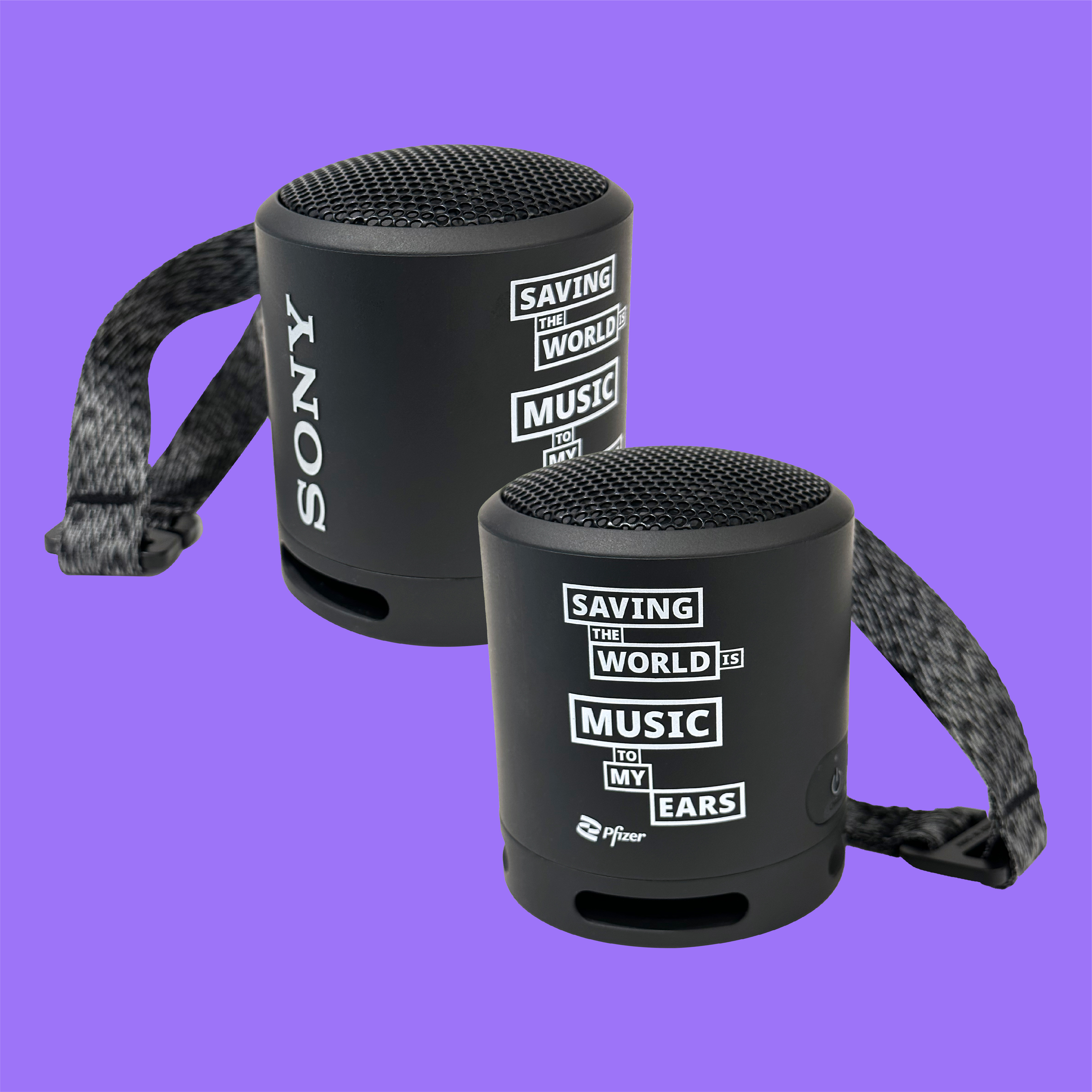 A black bluetooth speaker on a vibrant purple background with a wrist strap that has a Pfizer logo and "saving the world is music to my ears" printed in white lettering.