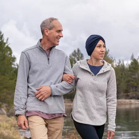 Imagen de un hombre y una mujer con los brazos entrelazados caminando al aire libre – Estudios clínicos de Pfizer