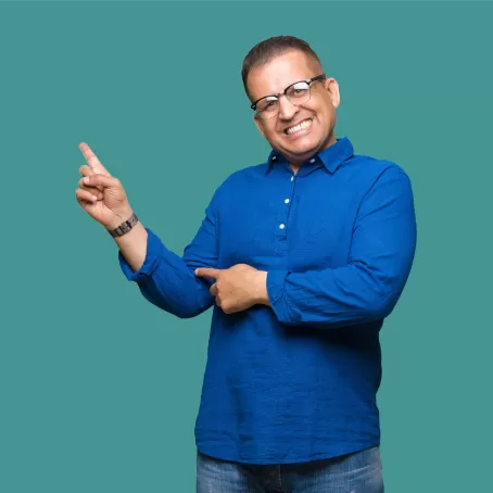A healthy clinical trial volunteer in a blue button-up points to the left and smiles against a teal background.