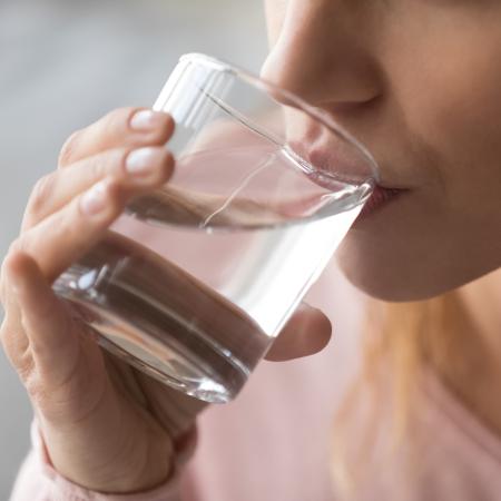 A close up of a person sipping water out of a glass