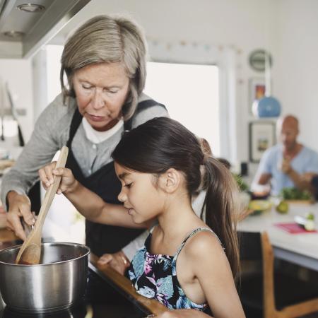grandmother looking at girl cooking at kitchen counter – Pfizer Clinical Trials