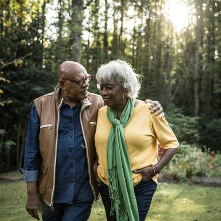 A couple embracing in a forest, the husband gently wrapping his arm around his wife’s shoulder while he smiles at her – Pfizer Clinical Trials