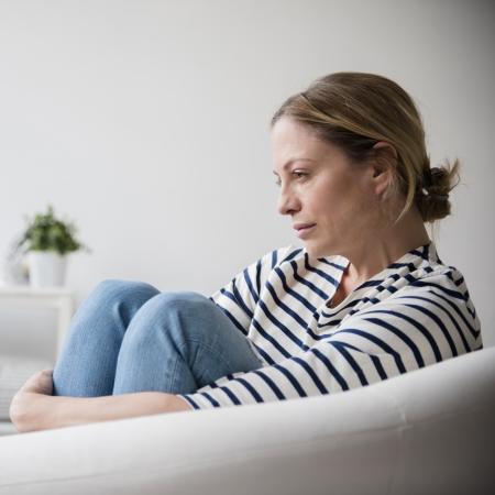 Woman on couch with knees to her chest – Pfizer Clinical Trials