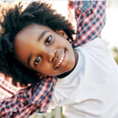 Young child jumping and smiling at camera – Pfizer Clinical Trials
