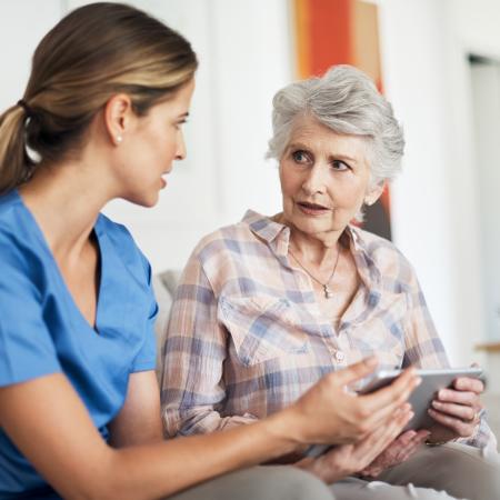 Older female patient sitting next to a female doctor – Pfizer Clinical Trials